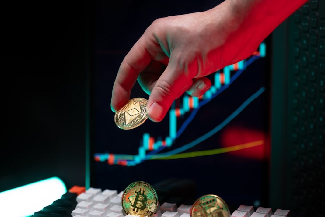 Hand holding ethereum with crypto graphs in background.