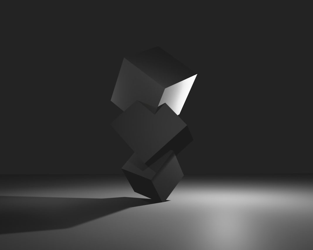 Black cubes balanced against a dark backdrop.