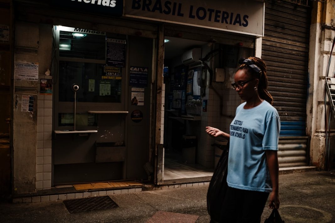 A woman walks past a brasil loterias store at night.